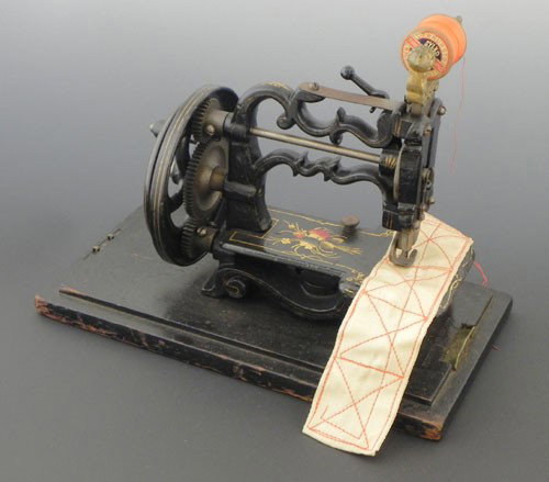 Diminutive Cast Iron Hand Operated Sewing Machine: Diminutive Cast Iron Hand Operated Sewing Machine, 19th c., pat. 1869, with original gilt and floral transfer decoration, in original ebonized case, Case- H.- 9 5/8 in., W.- 11 3/4 in., D.- 6 1/4 in.,