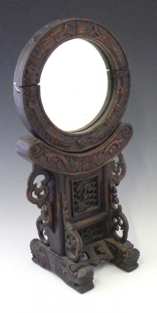 Chinese Carved Mahogany Circular Dressing Mirror,: Chinese Carved Mahogany Circular Dressing Mirror, late 19th c., with a relief dragon carved frame, on a pierced and carved stand with trestle supports on dragons' head feet, the mirror removable for u