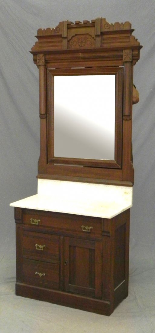 Eastlake Carved Birch Marble Top Washstand, c. 189: Eastlake Carved Birch Marble Top Washstand, c. 1890, with a carved crest over a central mirror, on a base with a white marble top and back splash, over a frieze drawer, above two drawers left and a cu