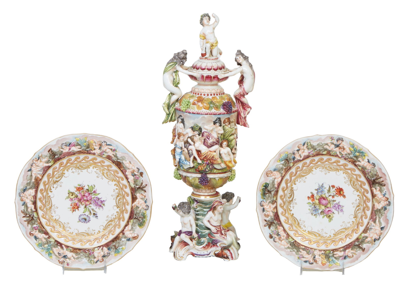Three Pieces of Capodimonte, 20th c., H.- 22 1/2 in., W.- 9 in., D.- 7 in. (3 Pcs.): Three Pieces of Capodimonte, 20th c., consisting of a pair of platters with relief borders of frolicking putti around a gilt bordered floral center, verso with a Capodimonte crown mark and "Made in Fr