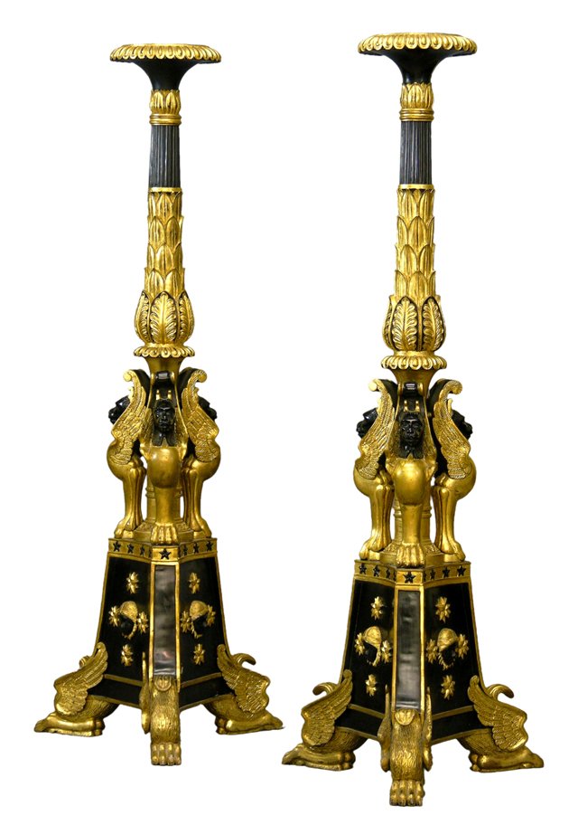 Pair of Carved and Ebonized Gilt Wood Egyptian Rev: Pair of Carved and Ebonized Gilt Wood Egyptian Revival Torcheres, 20th c., the scalloped circular top on a reeded and leaf mounted support, flanked by three gilt winged cat figures, on a tripodal slop
