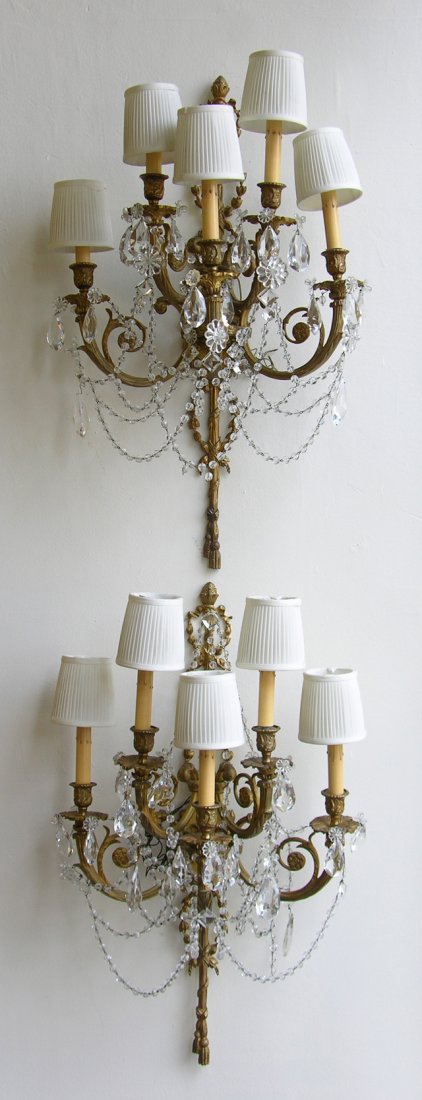 Pair of Louis XV Style Brass Five Light Wall Sconc: Pair of Louis XV Style Brass Five Light Wall Sconces, 20th c., with a torch and garland back plate issuing five relief decorated scrolled arms, hung with prisms and prism chains, H.- 28 1/2 in., W.- 1