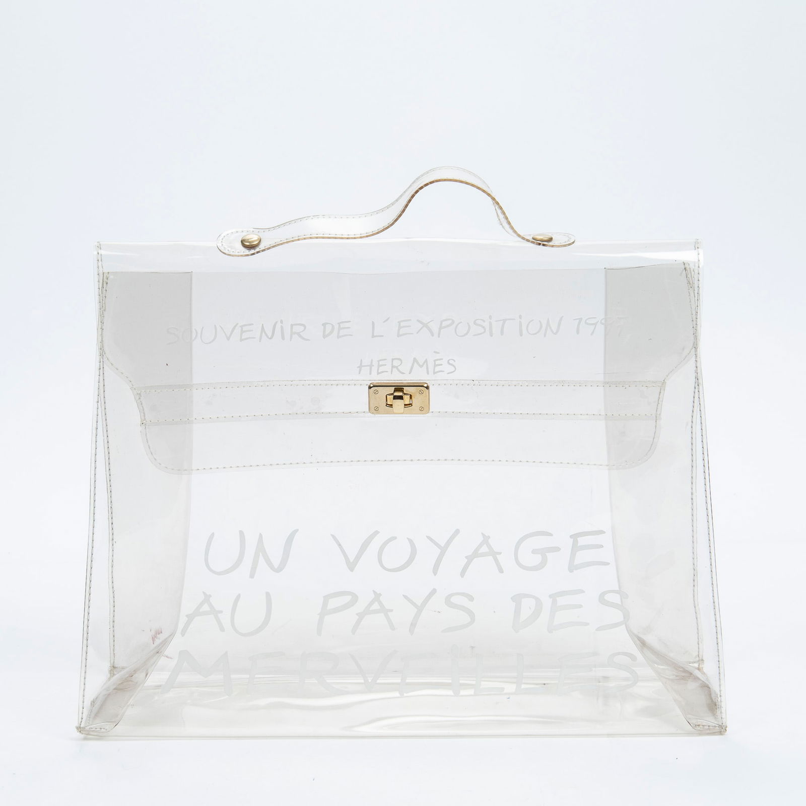 Hermes Limited Edition, Souvenir de L'Exposition Kelly Handbag, 1997, H.- 12 in., W.- 15 1/2 in.: Hermes Limited Edition, Souvenir de L'Exposition Kelly Handbag, 1997, in transparent vinyl, with brass hardware and white script "Souvenir de L'Exposition 1997/ Hermes/ Un Voyage au Pays des Merveille