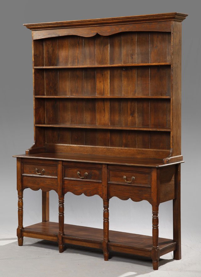 English Carved Oak Welsh Dresser, c. 1880, the ste: English Carved Oak Welsh Dresser, c. 1880, the stepped ogee crown over a shelved back, on a base with three frieze drawers over a deep scalloped skirt, on turned supports to a lower shelf, the whole o