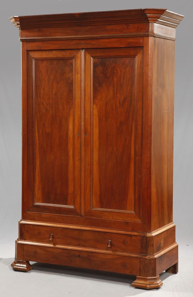 Louis Philippe Carved Walnut Armoire, c. 1850, the: Louis Philippe Carved Walnut Armoire, c. 1850, the stepped canted corner crown over double paneled doors above a lower drawer and a bottom "secret" drawer, the whole on large stepped ogee block feet, 