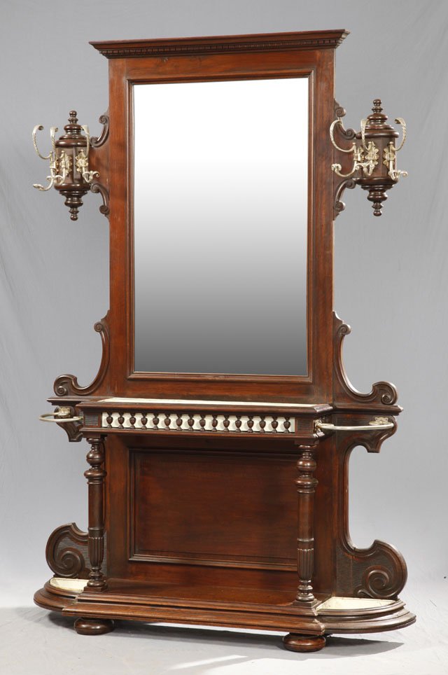 Large Carved Mahogany Hall Stand, c. 1900, the cen: Large Carved Mahogany Hall Stand, c. 1900, the central beveled mirror with a dentillated crown, flanked by large brass coat hooks, over a central removable metal tray, flanked by curved brass umbrella