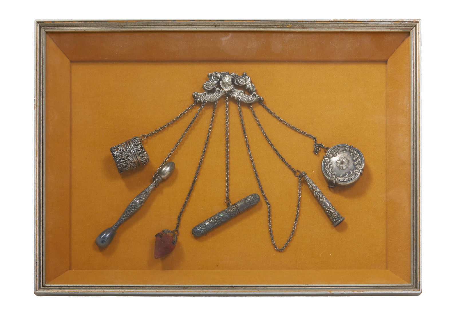 Sterling Silver Repousse Chatelaine, early 20th c., H.- 10 1/2 in., W.- 14 in., D.- 1 1/2 in.: Sterling Silver Repousse Chatelaine, early 20th c., with a scrolled relief brooch with six silver chains suspending two cylindrical boxes, a strawberry, a glove darning ball, a needle case, and smoker