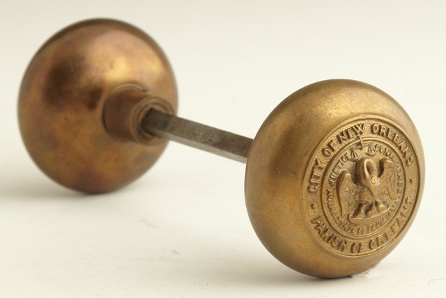 Pair of Bronze Door Knobs, early 20th c., with re: Pair of Bronze Door Knobs, early 20th c., with relief decoration of the state seal of Louisiana, marked "City of New Orleans, Parish of Orleans," with the connecting steel shaft, from the Wildlife and