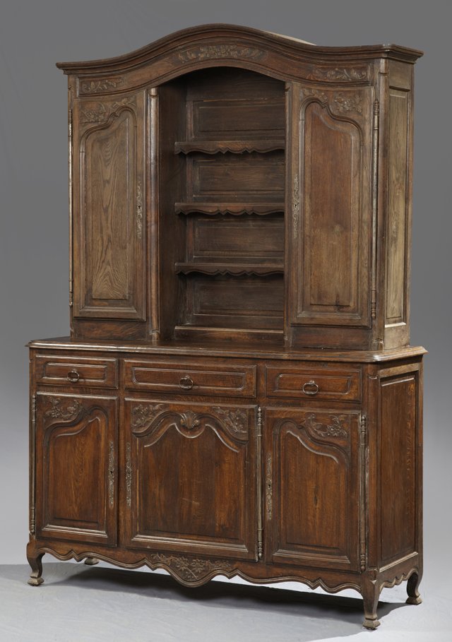 Louis XV Style Carved Oak Vaisselier, late 19th c., the: Louis XV Style Carved Oak Vaisselier, late 19th c., the arched rounded corner stepped crown with floral and leaf carving, over open central shelves, flanked by fielded panel cupboards with floral and 
