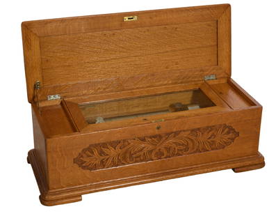 Carved Oak Jacot's Cylinder Music Box, c. 1880, H.- 12 in., W.- 36 in., D.- 14 1/2 in.: Carved Oak Jacot's Cylinder Music Box, c. 1880, the hinged lid opens to reveal music box works, with foliate carved front panel, on block feet, with crank, playing, H.- 12 in., W.- 36 in., D.- 14 1/2
