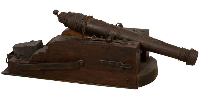 Spanish Cast Iron Cannon, 19th c., H.- 25 in., W.- 52 in., D.- 17 in.: Spanish Cast Iron Cannon, 19th c., the cast cannon with a tapering decorated body, mounted in a wooden cradle stand, H.- 25 in., W.- 52 in., D.- 17 in.