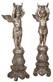 Pair of Silvered Metal Cherub Floor Torchieres, 20th c., Each- H.- 61 in., W.- 15 in., D.- 18 in. (2: Pair of Silvered Metal Cherub Floor Torchieres, 20th c., the draped winged figures with arms over head, above a decorated baluster shaped base with scrolled feet, Each- H.- 61 in., W.- 15 in., D.- 18
