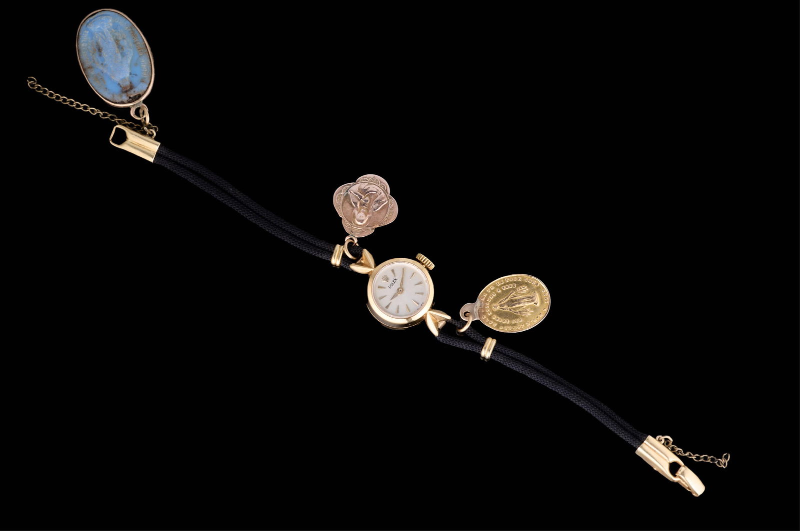 14K Yellow Gold Rolex Precision Watch, App. Wt.- 14.4 grams; Case- Dia.- 15 mm; L.- 6 1/4 in.: 14K Yellow Gold Rolex Precision Watch, on a corded band with three attached devotional charms, App. Wt.- 14.4 grams; Case- Dia.- 15 mm; L.- 6 1/4 in. Provenance: The Estate of William Prentice Farring
