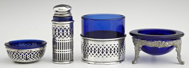 Group of Four Cobalt Glass Items, early 20th c., consis: Group of Four Cobalt Glass Items, early 20th c., consisting of a 3 piece sterling set of a salt, a pepper shaker, and a tabasco bottle holder, together with a German silver plated salt cellar. (4 Pcs.