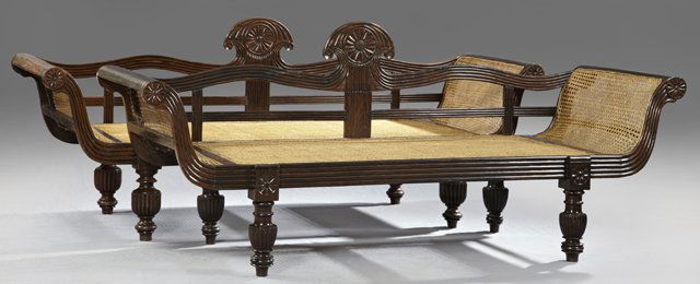 Pair of Burmese or Indian Carved Rosewood Settees, 20th: Pair of Burmese or Indian Carved Rosewood Settees, 20th c., the back with a central carved flower flanked by reeded rails, over a caned seat and outward curved caned sides, on turned and reeded legs,
