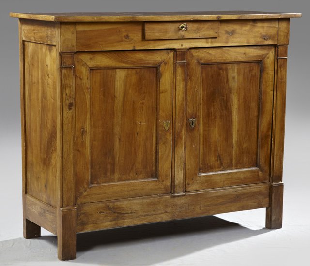 Louis Philippe Carved Walnut Sideboard, c. 1850, with a: Louis Philippe Carved Walnut Sideboard, c. 1850, with a central frieze drawer over double cupboard doors, each with a brass shield shaped escutcheon, the doors separated by a central carved column, th