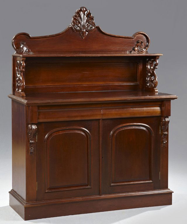 English Victorian Style Carved Mahogany Sideboard, 20th: English Victorian Style Carved Mahogany Sideboard, 20th c., the back with a shell carved crest atop an ogee edge shelf, on pierced tendril supports, on a base with two sloping front frieze drawers ove