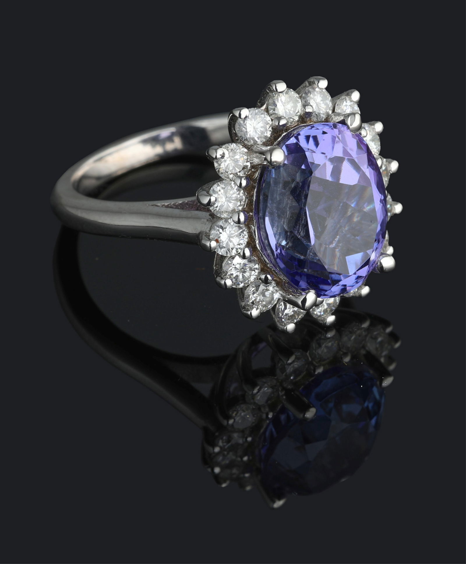 Ladies' 14K White Gold Tanzanite and Diamond Dinner Ring, Total Diamond Wt.- 1.03 carats, Size- 6: Ladies' 14K White Gold Tanzanite and Diamond Dinner Ring, the center mounted 6.88 carat oval tanzanite atop a border of 16 round white diamonds, Total Diamond Wt.- 1.03 carats, Size- 6 1/2. Please Not