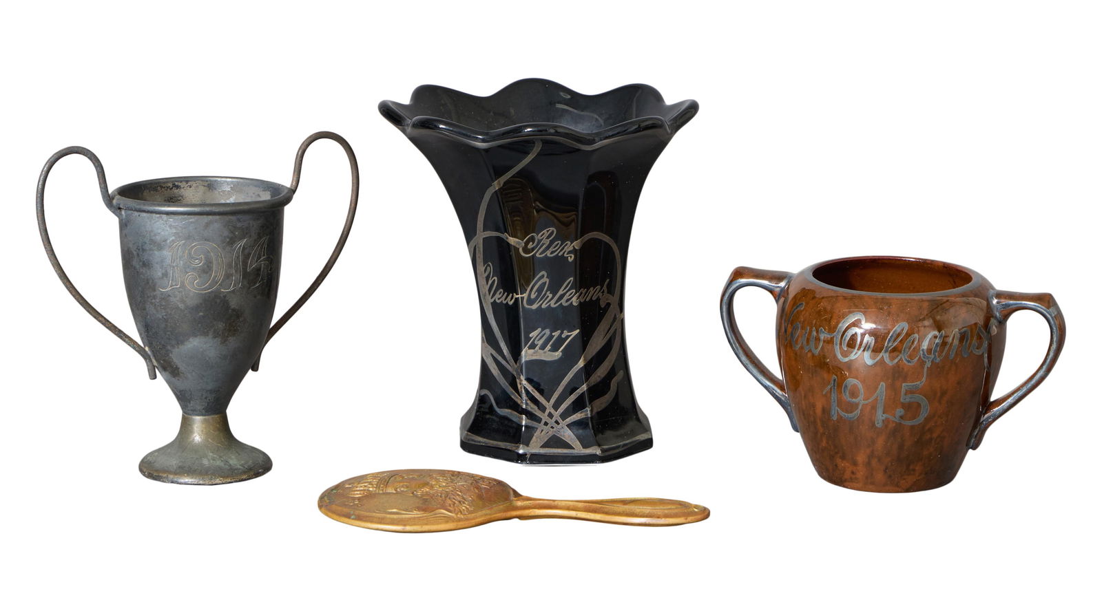 Four Mardi Gras Krewe Favors, Rex, early 20th c., 1912- H.- 6 1/4 in., W.- 3 1/8 in.; 1914- H.- 5: Four Mardi Gras Krewe Favors, Rex, early 20th c., the 1912 example in the form of a gilt metal hand mirror, from the theme "Phases of Nature," the 1914 example in in the form of a silver-plated loving