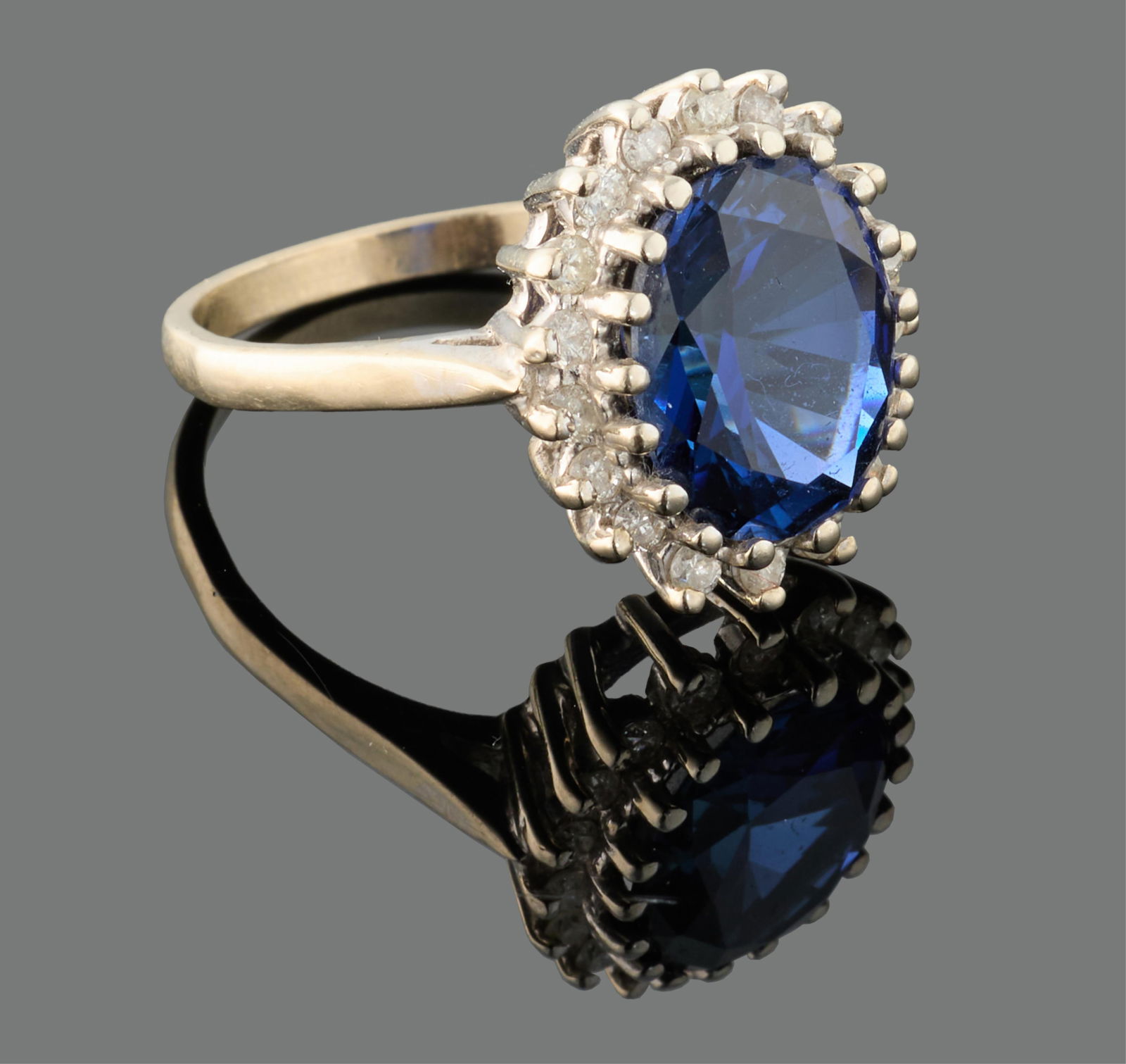 Ladies' 14K White Gold Sapphire and Diamond Dinner Ring, App. Total Diamond Wt.- 0.90 carats, Size-: Ladies' 14K White Gold Sapphire and Diamond Dinner Ring, the center mounted app. 4.5 carat oval blue sapphire within a conforming border of 18 small round white diamond points, App. Total Diamond Wt.-