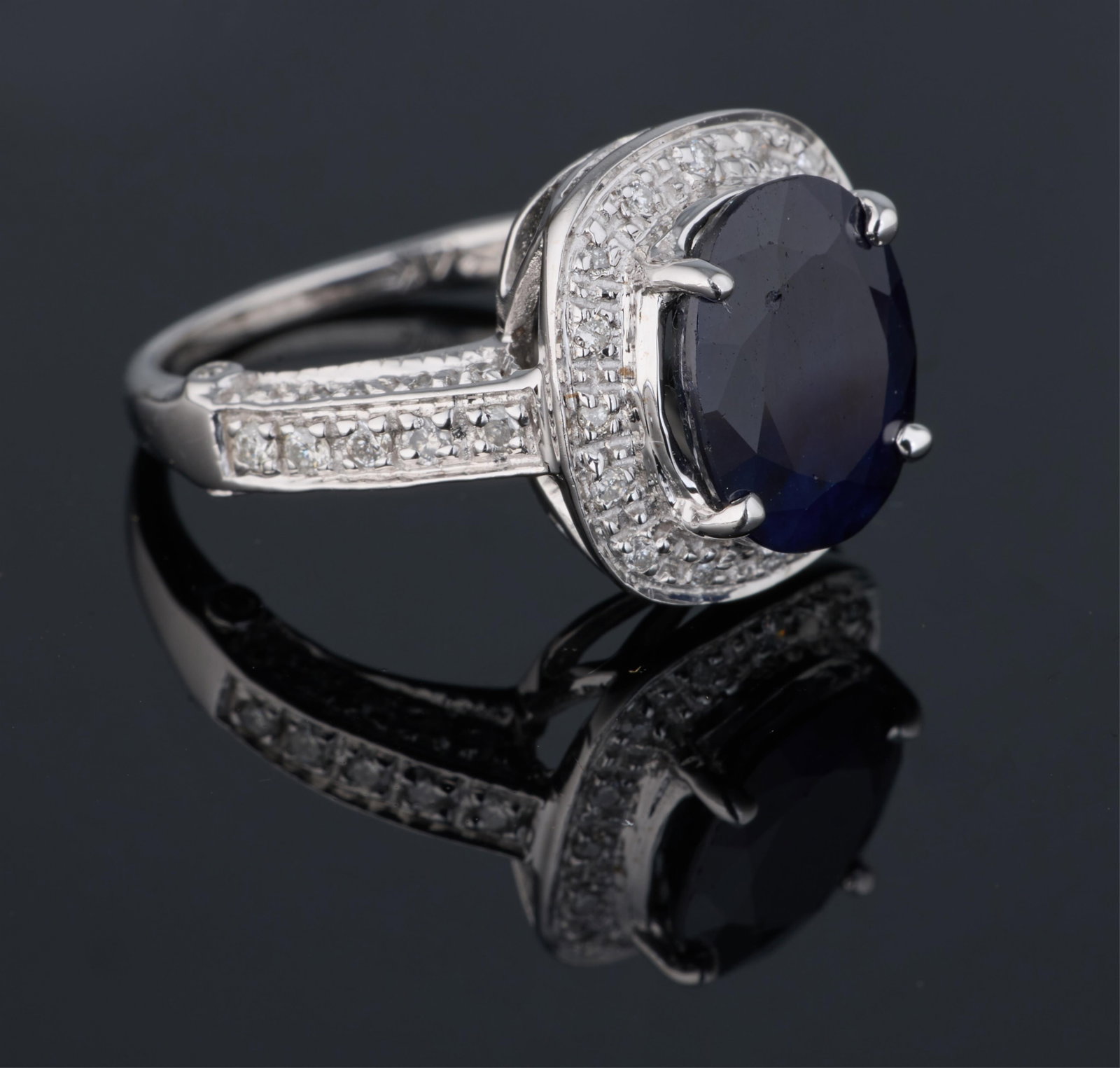 14K White Gold, Sapphire and Diamond Ring, App. Total Wt.- 3.9 grams, Size- 4 3/4.: 14K White Gold, Sapphire and Diamond Ring, the approximately 4.07 carat oval cut center mounted blue sapphire within a cushioned surround, surmounted atop channel set shoulders, the setting bearing ap