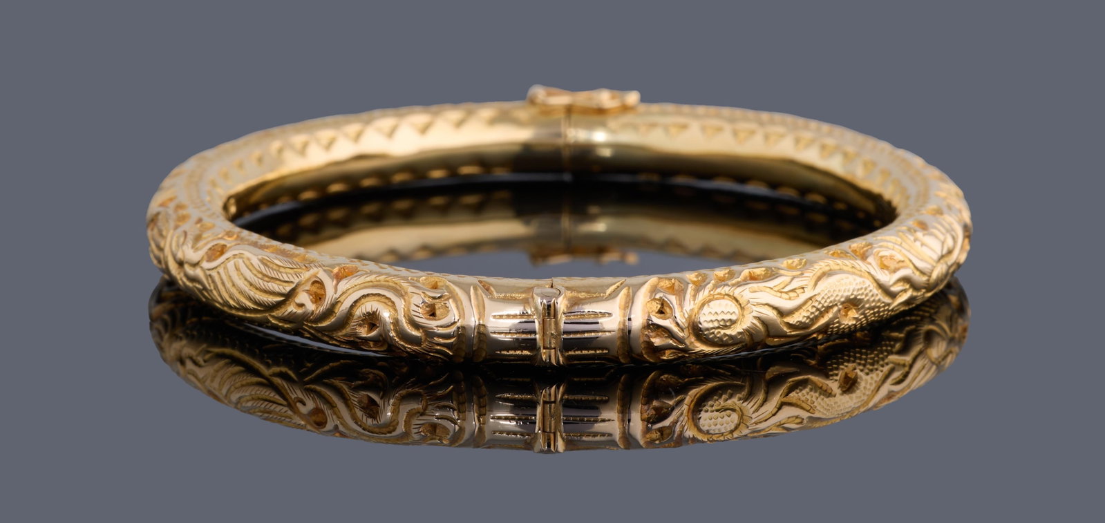 18K Yellow Gold Hinged Bangle, App. Total Wt.- 19 grams, Int. Dia.- 2 in.: 18K Yellow Gold Hinged Bangle, with Dragon & Phoenix motif, tongue in groove clasp, App. Total Wt.- 19 grams, Int. Dia.- 2 in. Please Note: All assessments of gemstone weight, color, and/or clarity ar