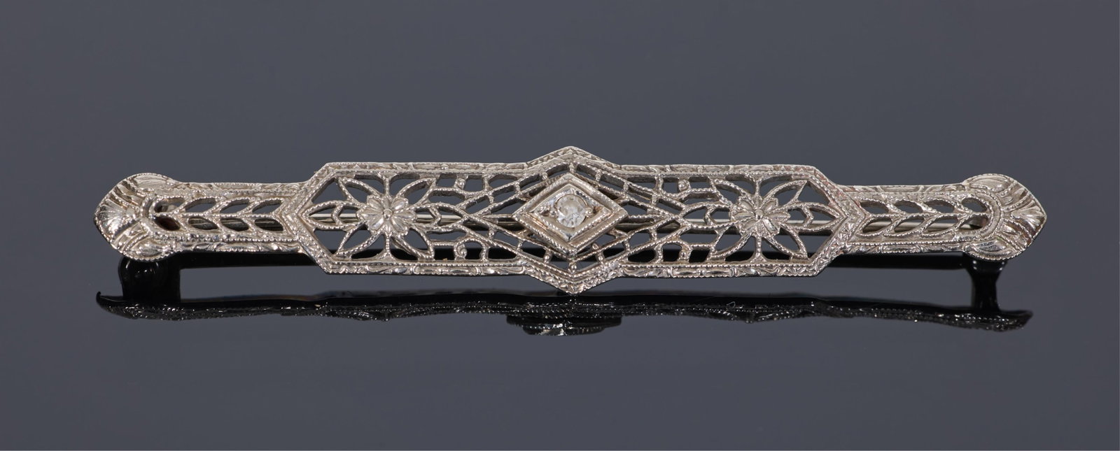 10K White Gold Art Deco Diamond Bar Pin, H.- 3/8 in., W.- 2 1/16 in.: 10K White Gold Art Deco Diamond Bar Pin, mounted with a small round white diamond in a floral filigreed design, H.- 3/8 in., W.- 2 1/16 in.