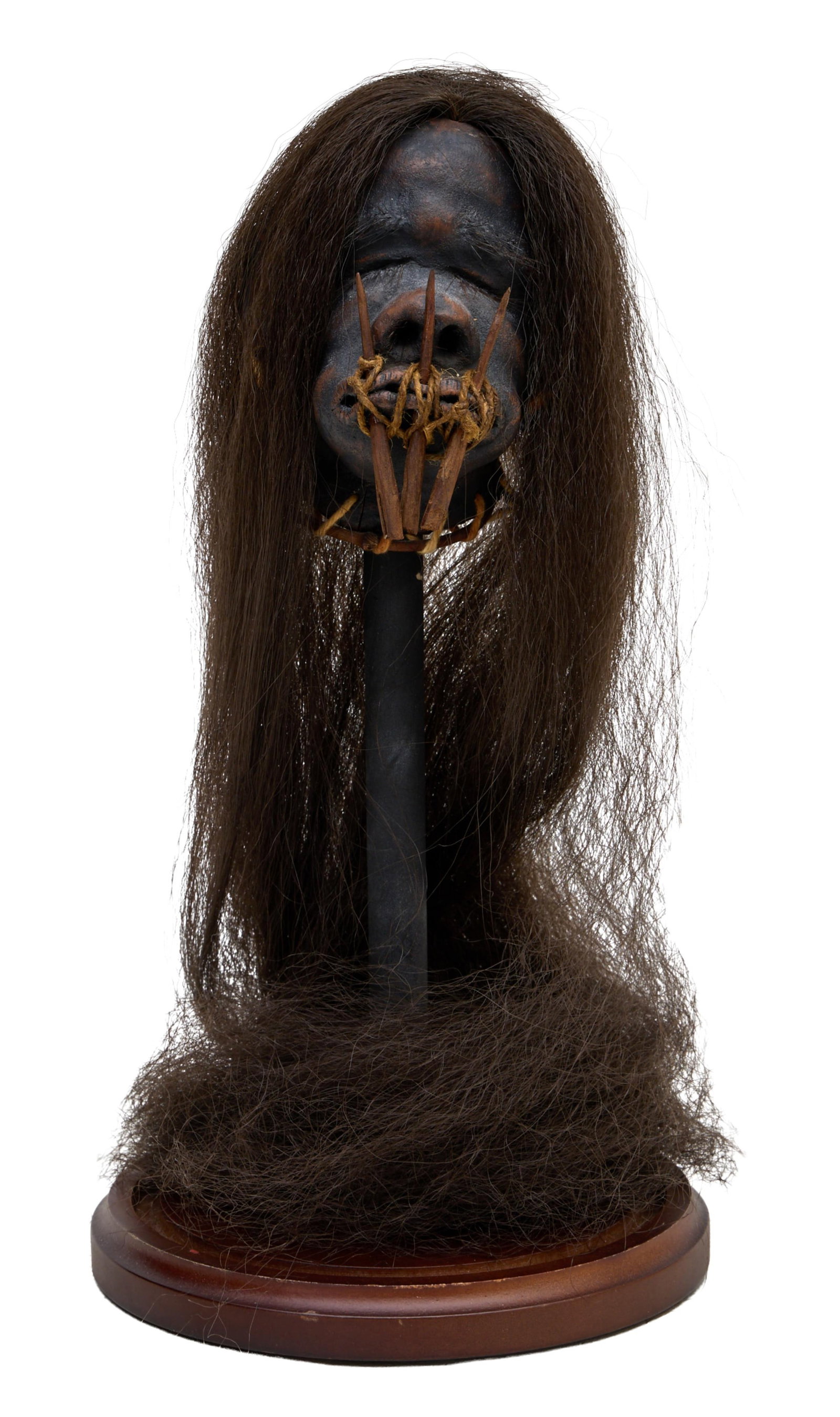 South American Tsantsa Shrunken Head Replica, 20th/21st c., On Stand- H.- in., 13 in., Dia.- 6 5/8: South American Tsantsa Shrunken Head Replica, 20th/21st c., molded clay with applied hair, the mouth pierced and sewn with chonta palm pins vertically through the lips and bound with fiber strings, di