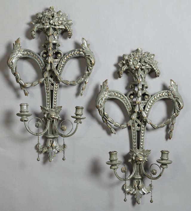 Pair of French Carved Wooden Two Light Sconces, early: Pair of French Carved Wooden Two Light Sconces, early 20th c., with fruit and floral basket surmounts over gryphon heads holding garlands, above two scrolled candle arms, now in green paint, H.- 25 in