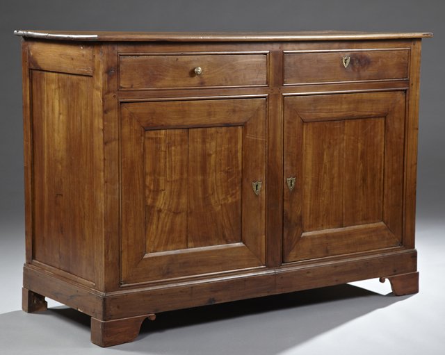 Louis Philippe Carved Cherry Sideboard, c. 1850, the: Louis Philippe Carved Cherry Sideboard, c. 1850, the rounded edge top over two frieze drawers, one with a brass shield escutcheon, over double fielded panel cupboard doors with brass shield escutcheon