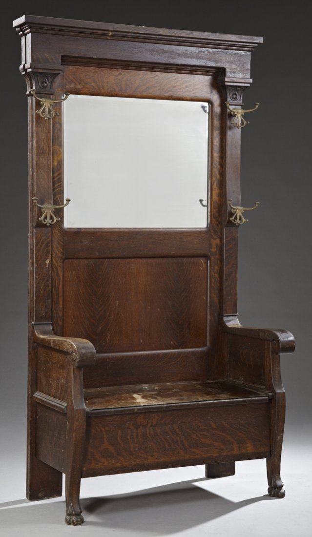American Victorian Carved Tiger Oak Hall Seat, late: American Victorian Carved Tiger Oak Hall Seat, late 19th c., the ogee crown over four gilt iron double coat hooks, flanking a central beveled mirror, to scrolled arms, flanking a lift top bench, all o