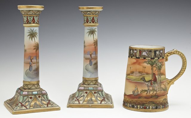 Three Pieces of Nippon Porcelain, 20th c., consisting: Three Pieces of Nippon Porcelain, 20th c., consisting of a pair of candlesticks and a tankard, each with scenes of a desert and palm trees, Candlesticks- H.- 8 3/4 in., W.- 4 1/8 in., D.- 4 1/8 in.