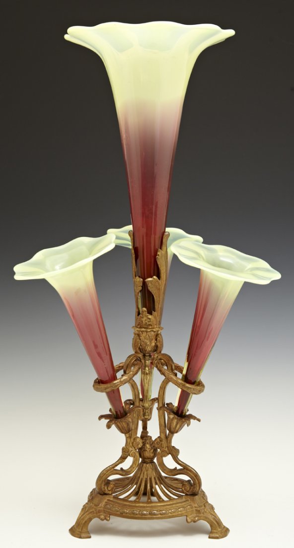 American Brass and Art Glass Epergne, early 20th c.,: American Brass and Art Glass Epergne, early 20th c., the four cranberry and vaseline glass scalloped trumpet vases on a pierced bronze base with relief floral decoration, H.- 19 1/4 in., Dia.- 10 1/2 