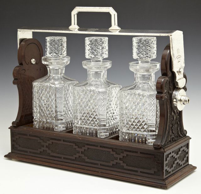 English Carved Mahogany Three Bottle Tantalus Set, c.: English Carved Mahogany Three Bottle Tantalus Set, c. 1900, marked Betjemann's Patent, London, with key, H.- 14 in., W.- 16 3/8 in., D.- 5 3/4 in.