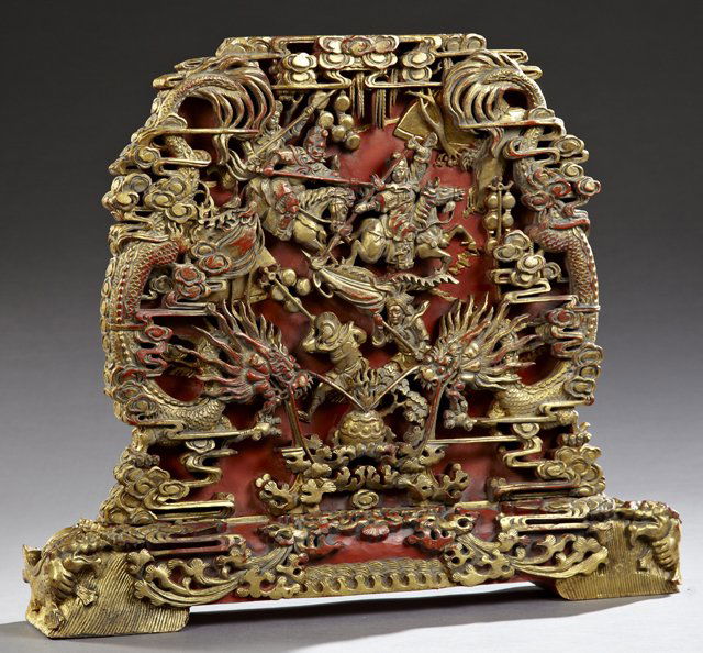 Chinese Carved Wood Table Screen, 20th c., the high: Chinese Carved Wood Table Screen, 20th c., the high relief carved gilt panel with clouds, a battle scene and dragons, with a cinnabar lacquer finish, on an integral trestle base carved with clouds, fo