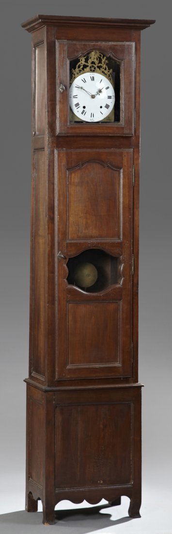 French Provincial Carved Cherry Tall Case Clock, early: French Provincial Carved Cherry Tall Case Clock, early 19th c, the ogee crown over a glazed door, the enameled dial with a pierced brass crest with angel decoration, over a paneled lower pendulum door