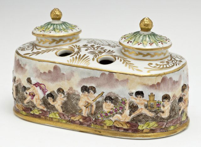 Capodimonte Porcelain Double Inkwell, 20th c., with: Capodimonte Porcelain Double Inkwell, 20th c., with gilt and polychromed decoration, the sides with relief decoration of frolicking putti, with lids and porcelain inkpots, H.- 4 in., W.- 6 3/8 in., D.