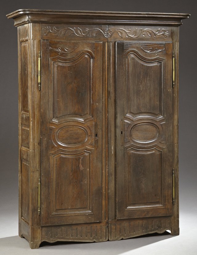 French Provincial Louis XVI Style Carved Oak Armoire,: French Provincial Louis XVI Style Carved Oak Armoire, 19th c. and later, the stepped ogee crown over a flower and tendril carved frieze, above double fielded panel doors with gilt iron fiche hinges, o
