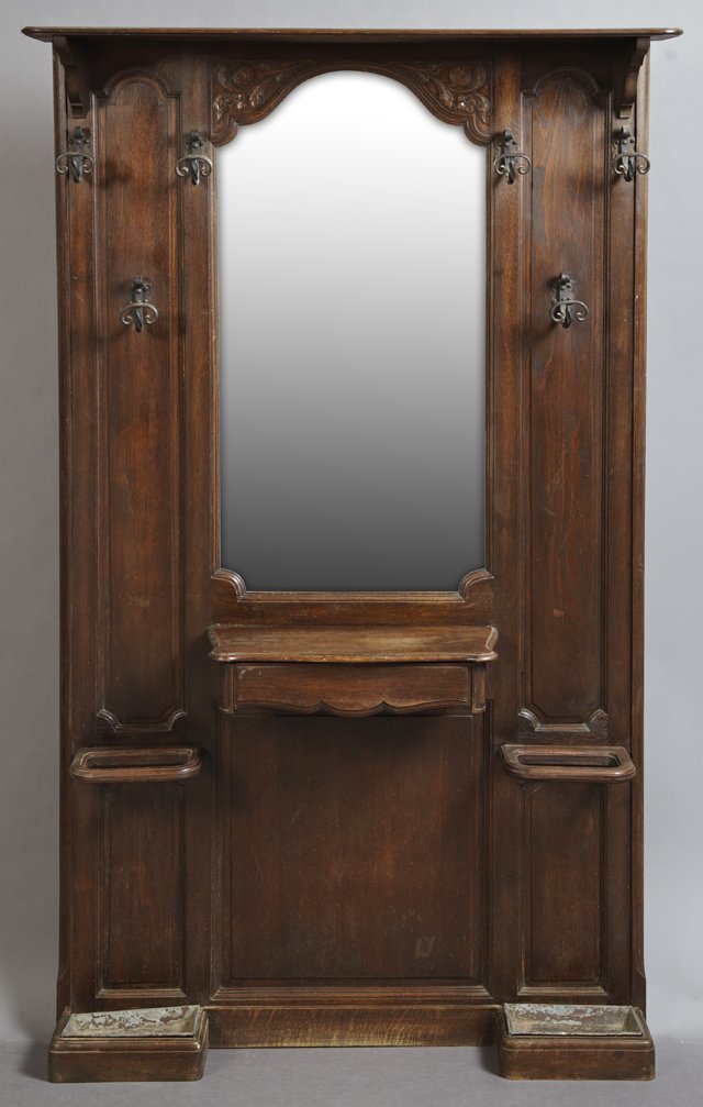 French Provincial Carved Oak Hall Tree, c. 1900, the: French Provincial Carved Oak Hall Tree, c. 1900, the hat shelf over an arched plate flanked by six wrought iron hooks, over a central glove drawer flanked by umbrella stands with tole painted drip tra