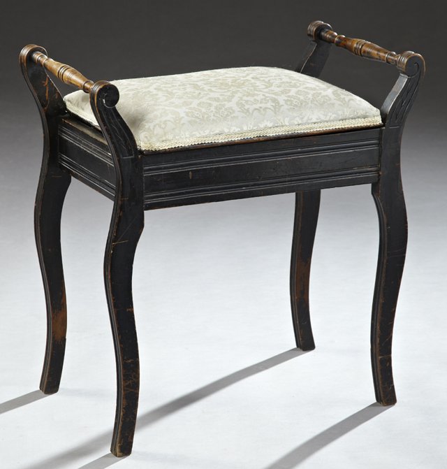 English Carved Mahogany Music Bench, c. 1900, the: English Carved Mahogany Music Bench, c. 1900, the cushioned seat over interior storage, flanked by ring turned tapered handles, on saber legs, joined by a wide reeded skirt, now in black paint and gre
