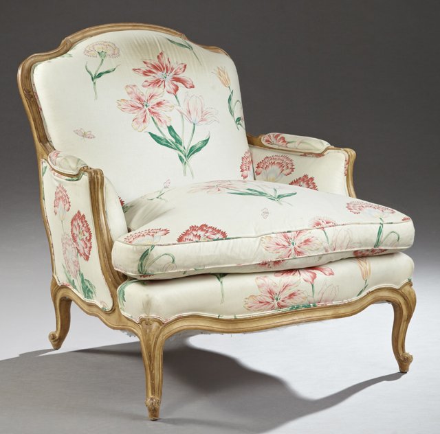 Louis XV Style Carved Birch Bergere, 20th c., the: Louis XV Style Carved Birch Bergere, 20th c., the arched back over a bowed seat cushion within bowed upholstered arms, on carved cabriole legs to scrolled feet on French toes, joined by a reeded skirt