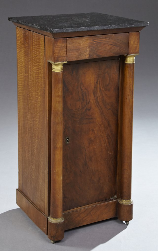 French Empire Ormolu Mounted Walnut Marble Top: French Empire Ormolu Mounted Walnut Marble Top Nightstand, 19th c., the figured square black marble over a frieze drawer above a cupboard door flanked by turned tapered ormolu mounted columns, on circ