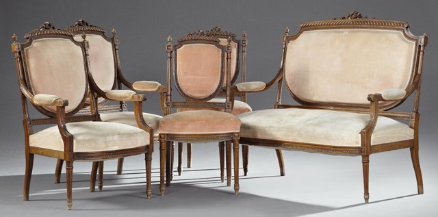 Five Piece French Louis XVI Style Carved Walnut Salon: Five Piece French Louis XVI Style Carved Walnut Salon Suite, 19th c., consisting of two side chairs, two armchairs, and a settee, all with pierced carved beribboned arched crests over upholstered shie