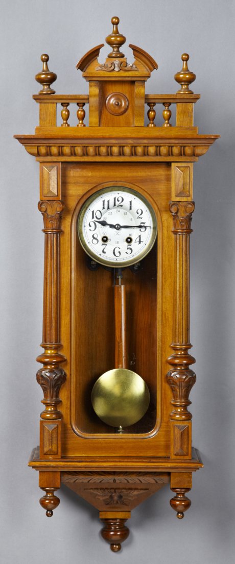 German Carved Walnut Wall Clock, c. 1900, time and: German Carved Walnut Wall Clock, c. 1900, time and strike, the broken arch crest with turned finials, over a spindled gallery above a glazed case, with a brushed steel dial, the bottom with turned fin
