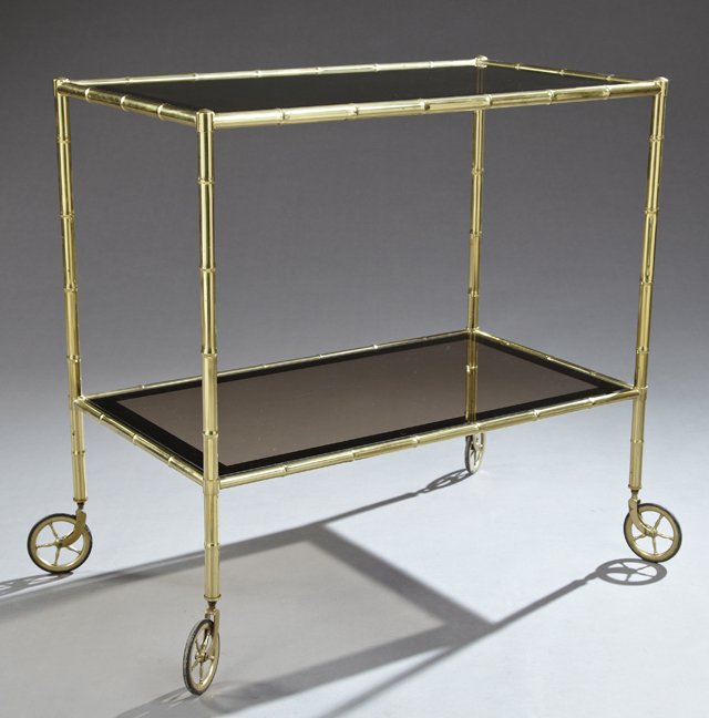 French Brass and Smokey Glass Tea Cart, 20th c., the: French Brass and Smokey Glass Tea Cart, 20th c., the inset rectangular glass top with a mirrored band within faux bamboo edges, on faux bamboo legs, to spoked wheels, joined by a like lower inset glas
