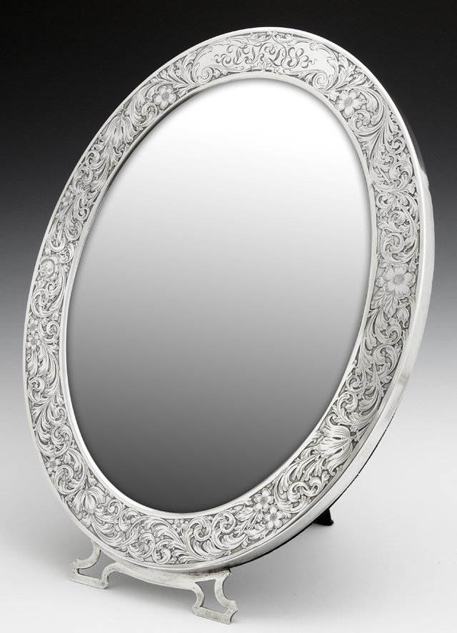 Unusual Sterling Easel Dressing Mirror, c. 1900, #1851,: Unusual Sterling Easel Dressing Mirror, c. 1900, #1851, the wide frame with relief floral and scrolled decoration around an oval beveled plate, H.- 15 1/2 in., W.- 12 1/2 in., D.- 5/8 in.