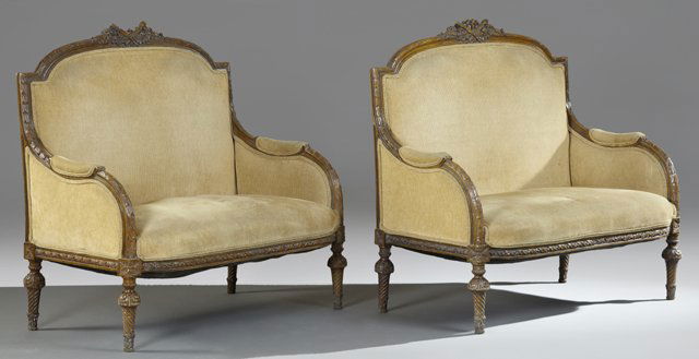 Pair of Louis XVI Style Carved Mahogany Settees, c.: Pair of Louis XVI Style Carved Mahogany Settees, c. 1900, the crest rails with floral, torch and quiver carving atop a leaf and berry carved frame with upholstered arms on twisted floral carved legs,