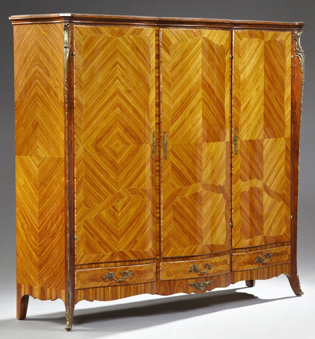 Ormolu Mounted Crotched Rosewood Triple Door Armoire,: Ormolu Mounted Crotched Rosewood Triple Door Armoire, early 20th c., the serpentine stepped crown over three serpentine doors over three lower drawers, flanked by ormolu mounted edges and bombe sides,