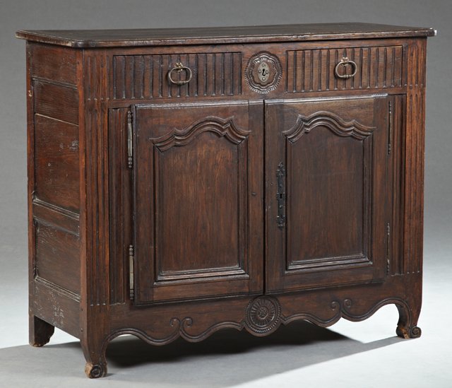 French Provincial Louis XV Style Carved Oak Sideboard,: French Provincial Louis XV Style Carved Oak Sideboard, 19th c., the curved corner rectangular top over two frieze drawers above two cupboard doors with short iron fiche hinges and a short iron escutch
