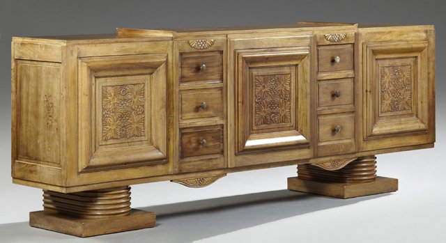 French Art Deco Carved Walnut Sideboard, early 20th c.,: French Art Deco Carved Walnut Sideboard, early 20th c., the stepped rectangular top over a central cupboard door, flanked by two banks of three drawers and cupboard doors, on ring turned legs to squar